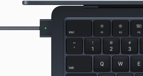 Tampilan atas yang memperlihatkan kabel MagSafe yang dicolokkan ke MacBook Air dalam warna Midnight