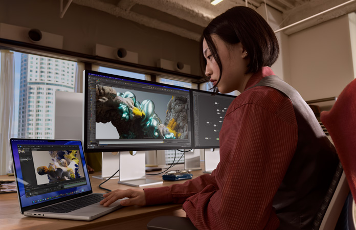 사무실 환경에서 MacBook Pro를 Studio Display XDR에 연결한 상태로 작업 중인 사람의 모습