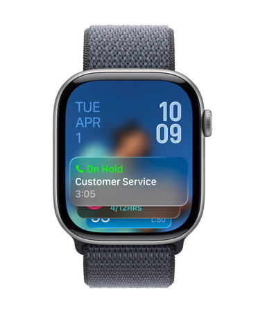 Kozmoszfekete Apple Watch zsályazöld szíjjal, a számlapon alul a Tartási asszisztens értesítése, felül a dátum, a jobb felső sarokban az időt mutató számjegyek egymás alatt