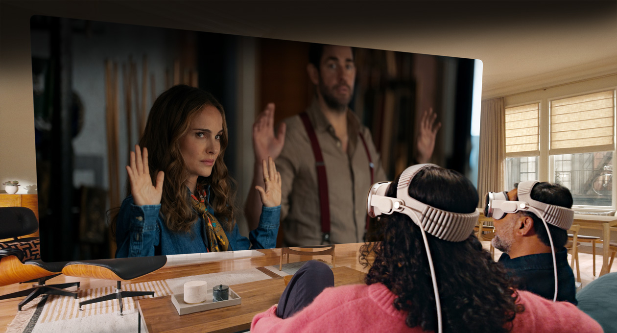 Apple Vision Pro를 착용한 두 사람이 소파에 나란히 앉아 방 전체에 펼쳐진 화면에 표시된 젊음의 샘 - Fountain of Youth 영화를 보고 있는 모습