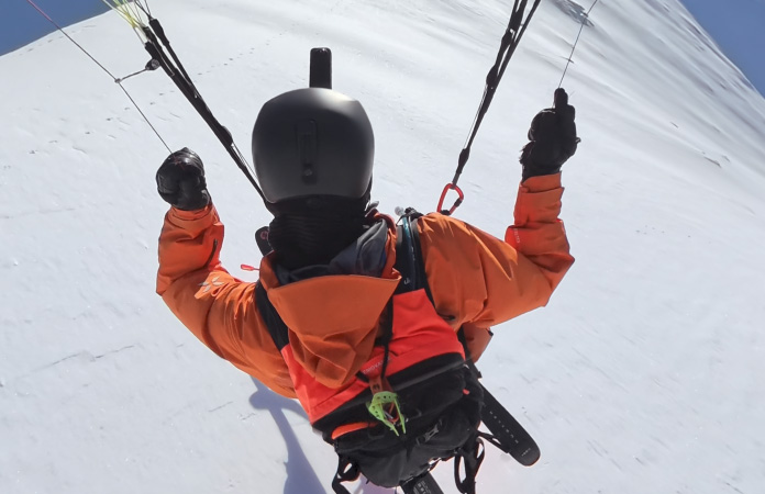 광시야각 장면 속 산꼭대기를 가로지르며 공중에서 패러스키를 타는 사람의 모습