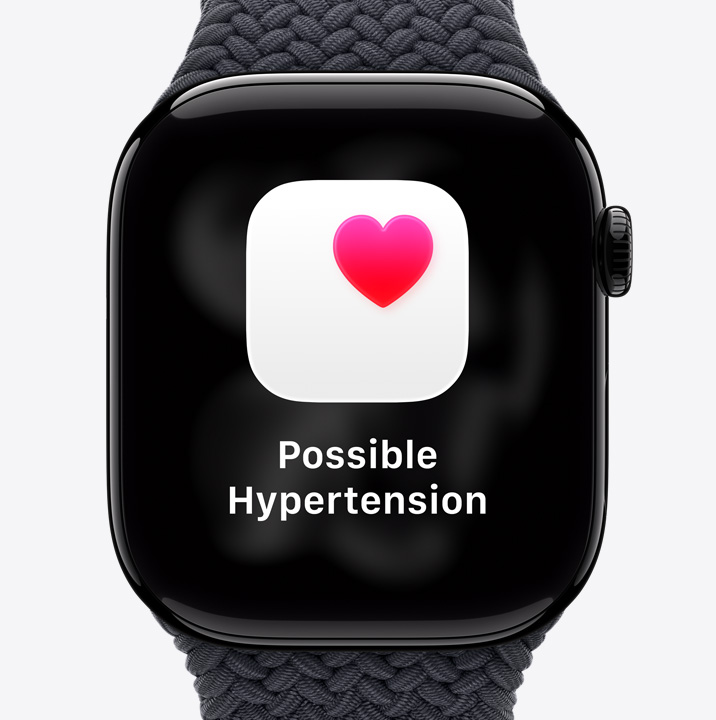 Apple Watch Series 11, hliníkový kryt v leštenej temnej čiernej farbe, hlásenie o možnej hypertenzii, ružové srdce v bielom poli, pohľad na pravú stranu, korunka Digital Crown, zapletaná slučka Solo v čiernej farbe